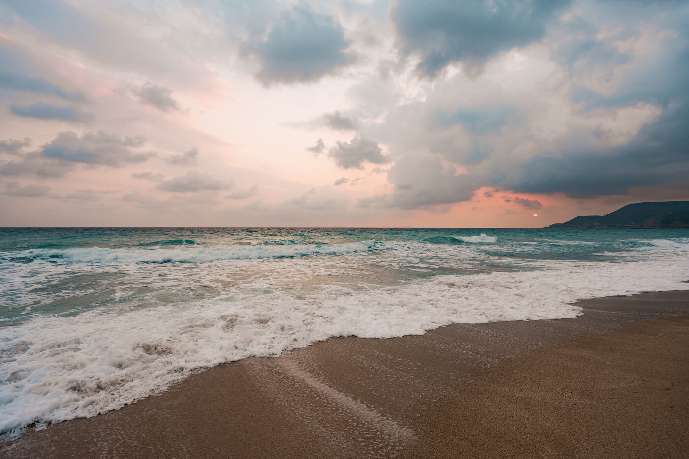 Waves rolling onto a beach under a soft sky